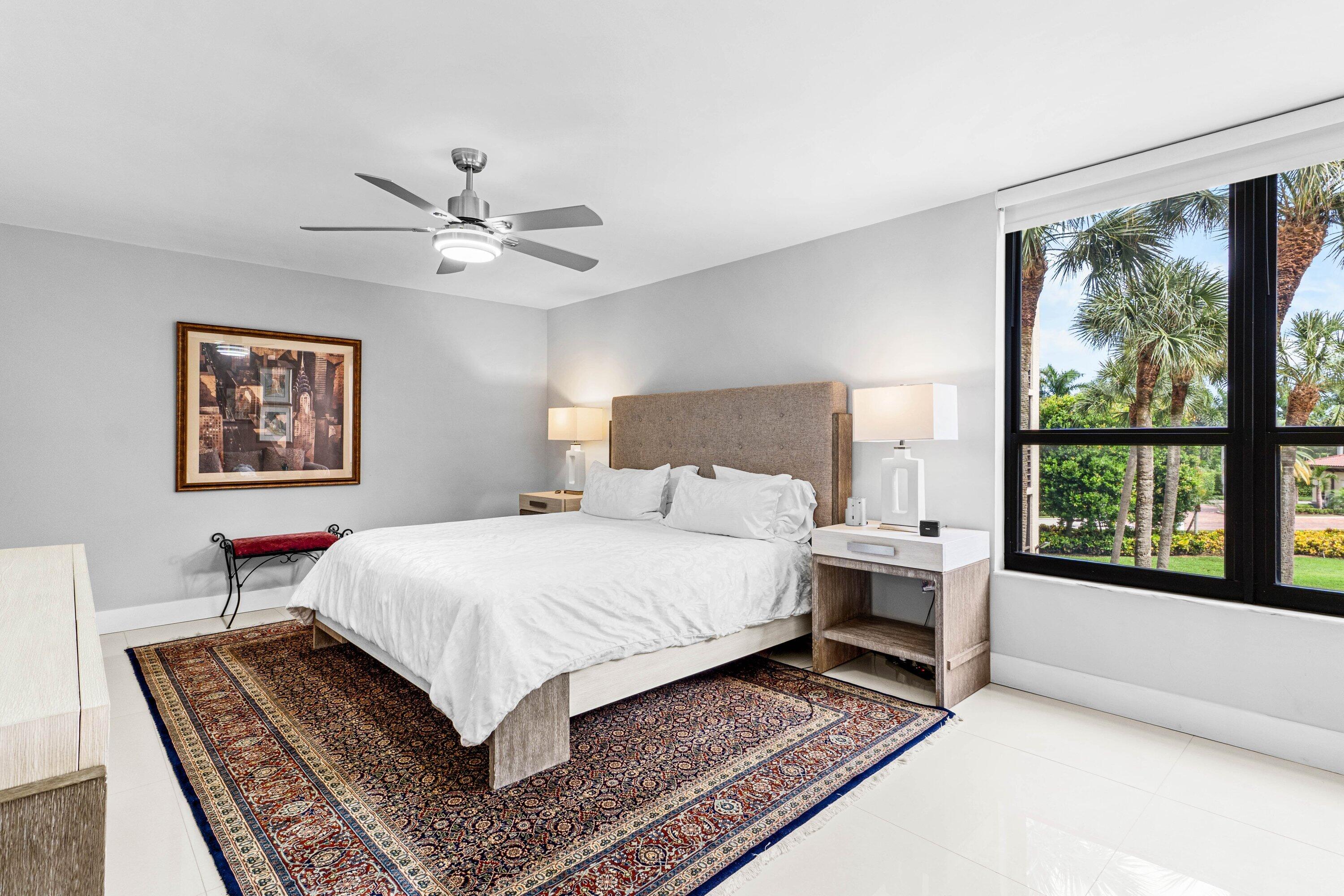 7572 Regency Lake Drive, Unit 301 Boca Raton, FL 33433 - Photo 21 of 38 a bedroom with a large bed a chandelier and windows