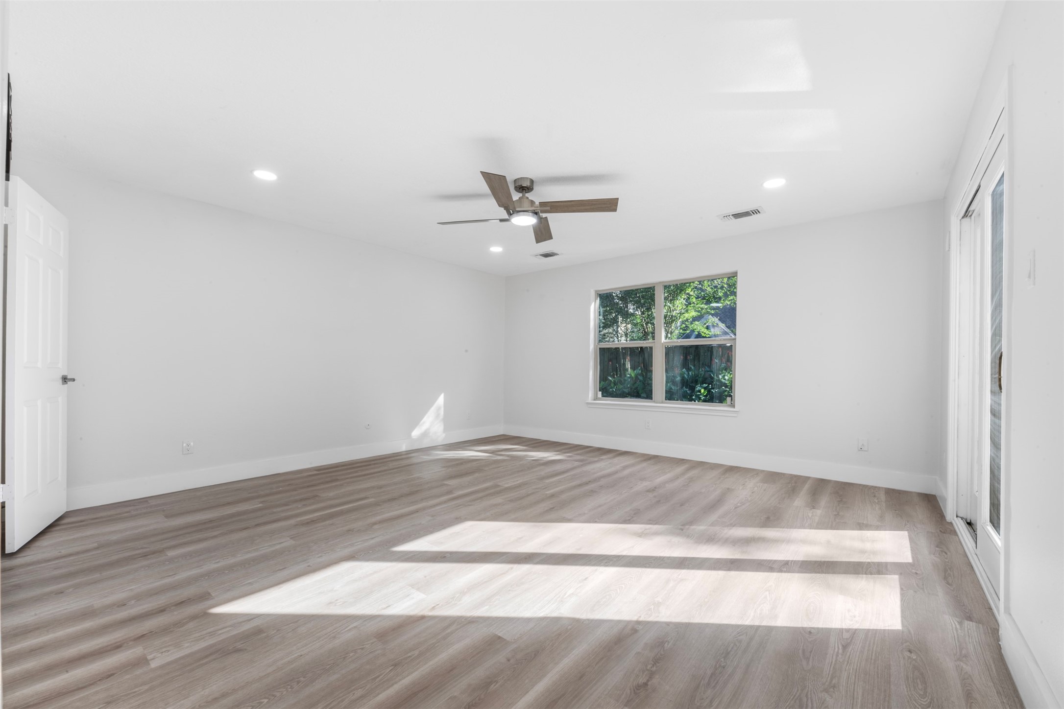 9543 Enstone Circle Spring, TX 77379 - Photo 19 of 50 Bright, spacious room with light wood flooring, a ceiling fan, and large windows offering plenty of natural light. Ideal for a living area or bedroom.