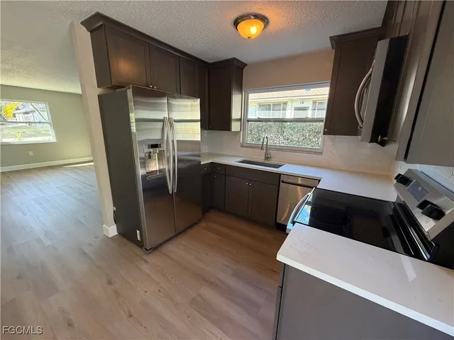 a kitchen with granite countertop a refrigerator a sink a stove and wooden floor