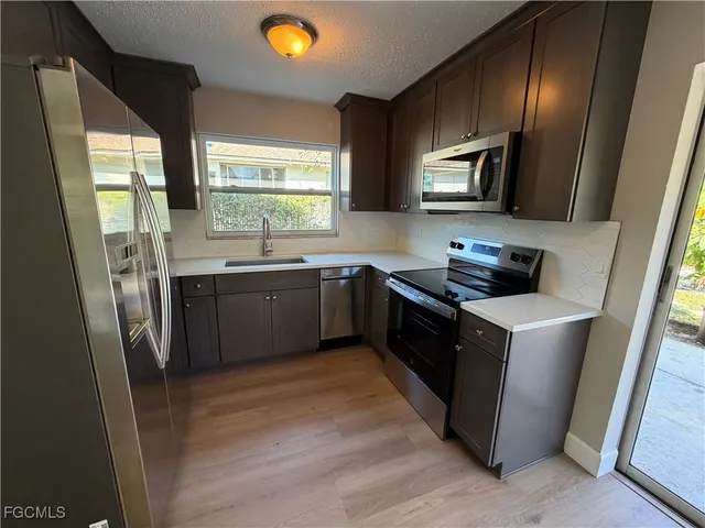 a kitchen with stainless steel appliances granite countertop a sink a stove a refrigerator cabinets and a window