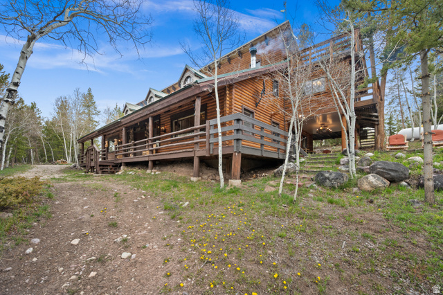 4725 Pine Ridge Road Evanston, UT 82930 - Photo 57 of 82 Log cabin exterior with a full-length covered porch, visible dormer windows, and a multi-level deck