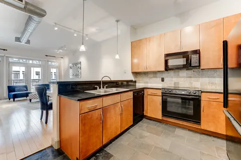 a kitchen with stainless steel appliances granite countertop a sink a stove top oven a counter space and cabinets