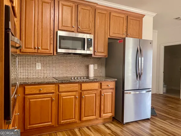a kitchen with granite countertop wooden cabinets stainless steel appliances and a window