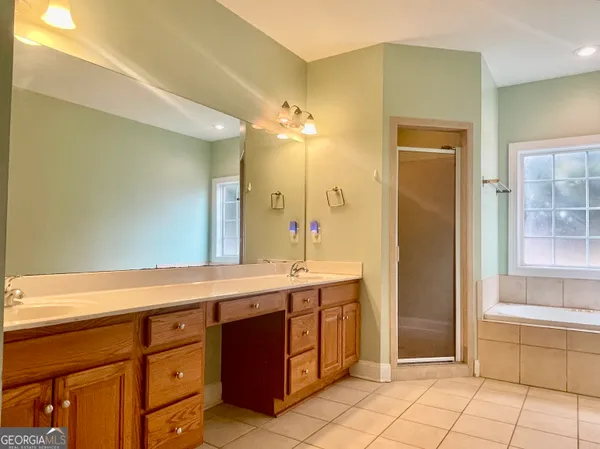a spacious bathroom with a granite countertop sink a mirror and a bathtub