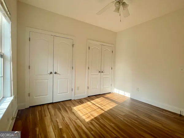 a view of empty room with wooden floor and fan