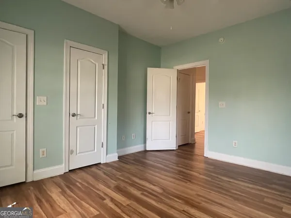 a view of an empty room with wooden floor and closet