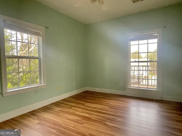 an empty room with wooden floor and windows