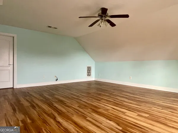 a view of a room with wooden floor and a ceiling fan