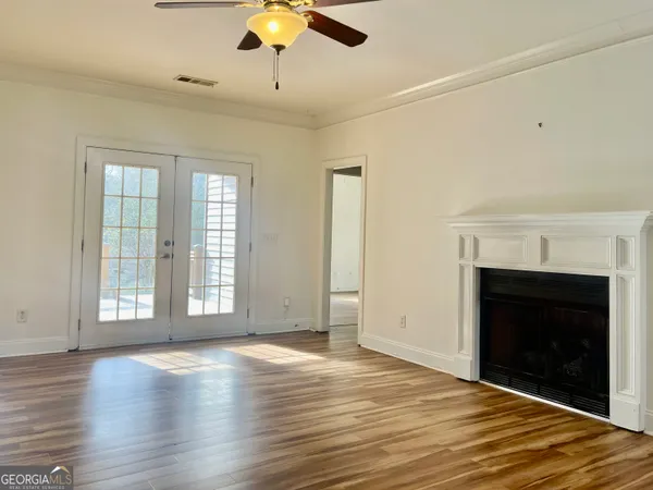 an empty room with wooden floor fireplace and windows