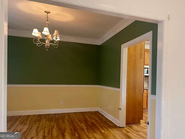 a view of a room with wooden floor and a chandelier