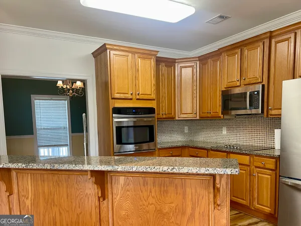 a kitchen with stainless steel appliances granite countertop a refrigerator a stove and a sink with wooden floor