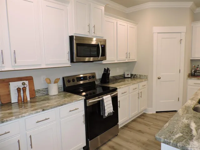 a kitchen with granite countertop white cabinets and stainless steel appliances