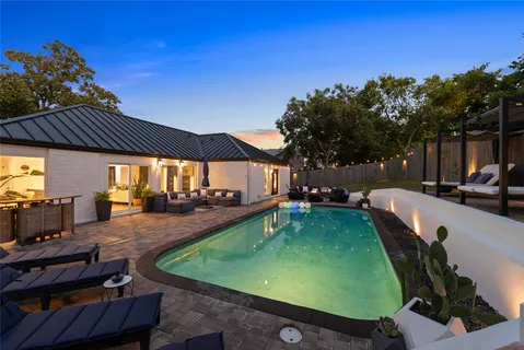 a view of a swimming pool with lawn chairs under an umbrella