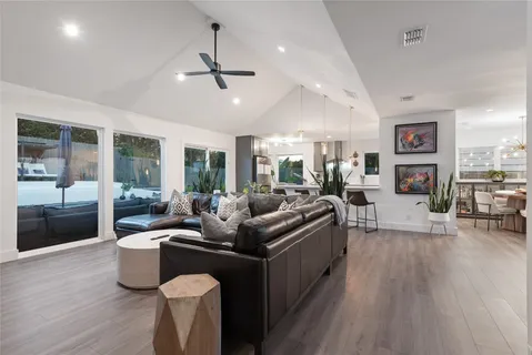 a living room with furniture a large window and wooden floor
