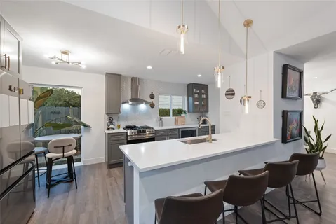 a kitchen with a dining table chairs sink and white cabinets