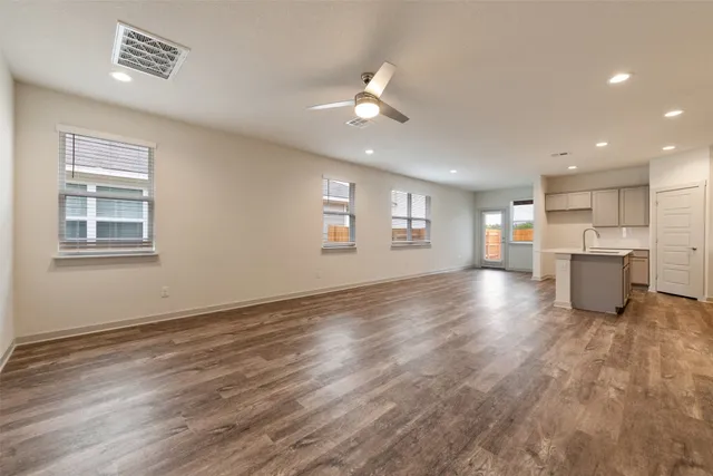 a view of an empty room with a window and wooden floor