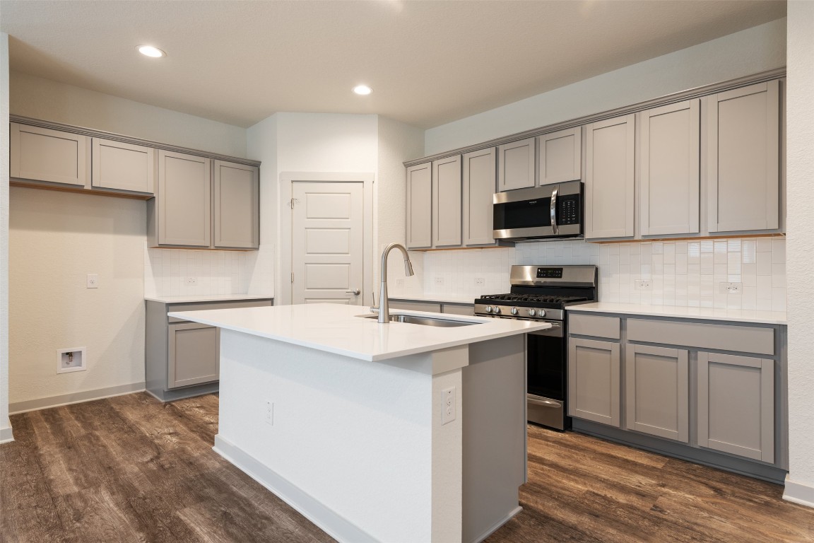 289 Deserti Road Leander, TX 78641 - Photo 5 of 19 a kitchen with stainless steel appliances granite countertop a stove top oven a sink and white cabinets