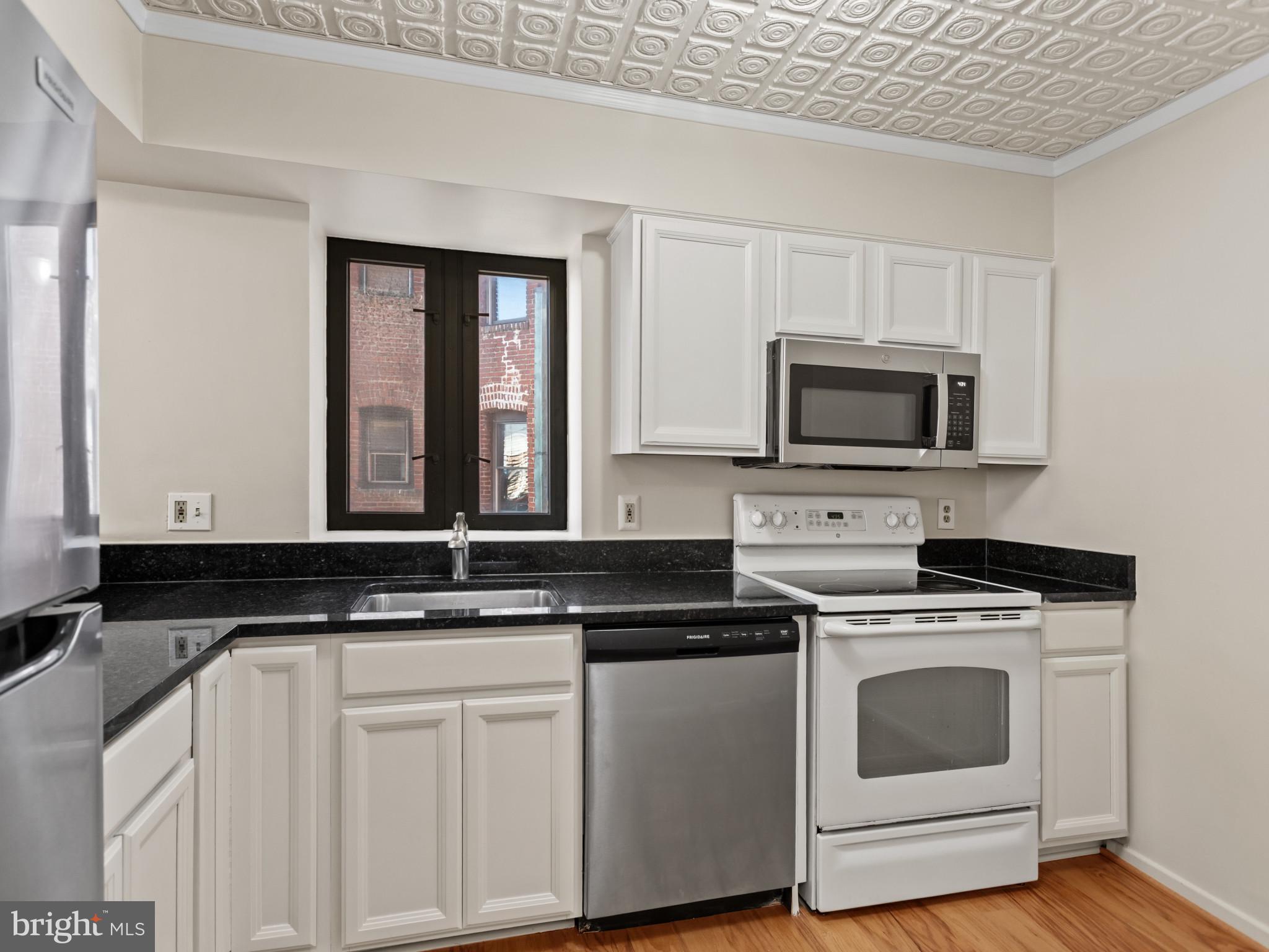 2320 Wisconsin Avenue Northwest, Unit 206 Washington, DC 20007 - Photo 6 of 32 a kitchen with granite countertop white cabinets and black appliances