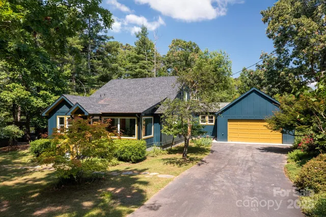 a view of a house with a small yard and large tree