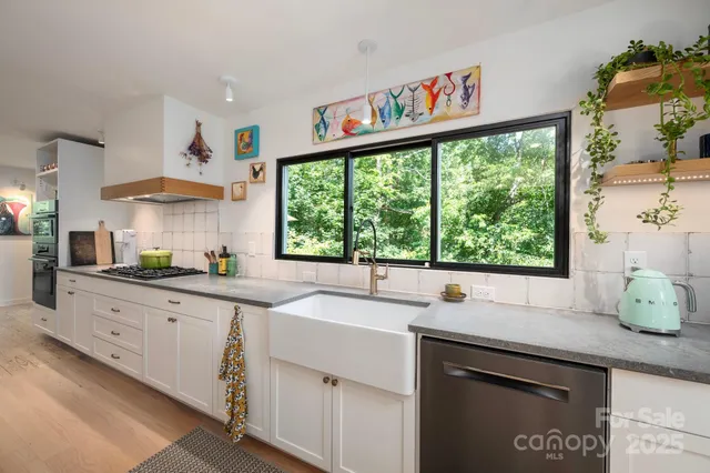 a kitchen with stainless steel appliances white cabinets and a large window