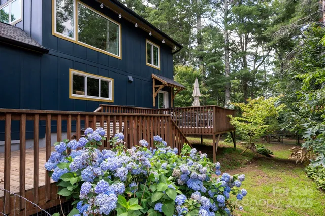 a view of a house with a flower garden and a bench