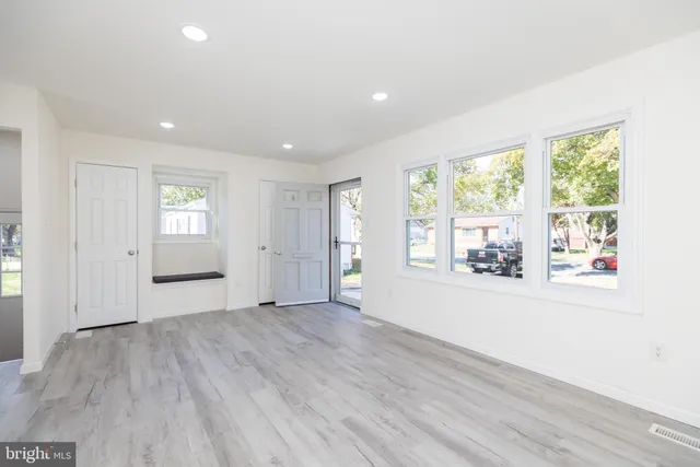 an empty room with wooden floor and windows