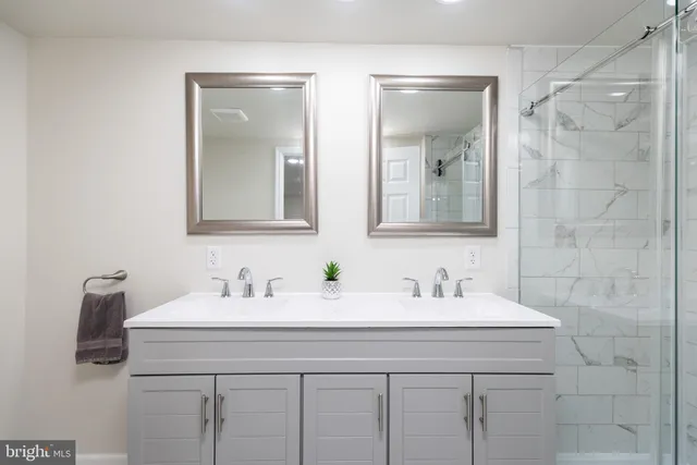 a bathroom with double sink and two mirror
