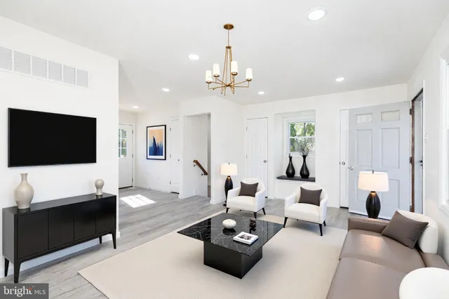 a living room with furniture a flat screen tv and a chandelier
