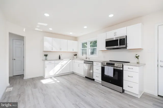 a large kitchen with cabinets wooden floor and stainless steel appliances