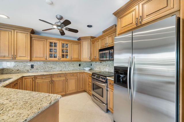 a kitchen with stainless steel appliances granite countertop a sink a stove a refrigerator a microwave oven with white cabinets and wooden floor