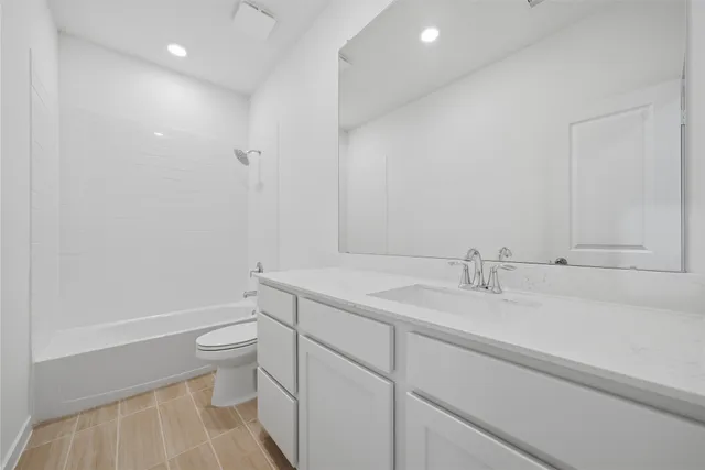 a bathroom with a granite countertop sink mirror vanity and toilet