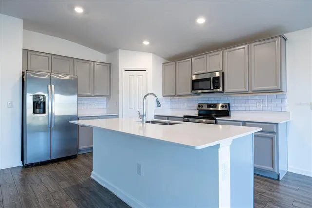 a kitchen with kitchen island a sink stainless steel appliances and cabinets
