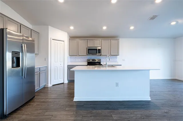 a kitchen with stainless steel appliances granite countertop a refrigerator a sink a stove a microwave and a refrigerator