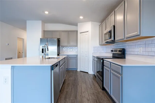 a kitchen with kitchen island granite countertop a sink a counter top space stainless steel appliances and cabinets