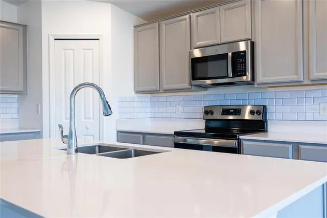 a kitchen with stainless steel appliances a stove a microwave a sink a refrigerator and white cabinets
