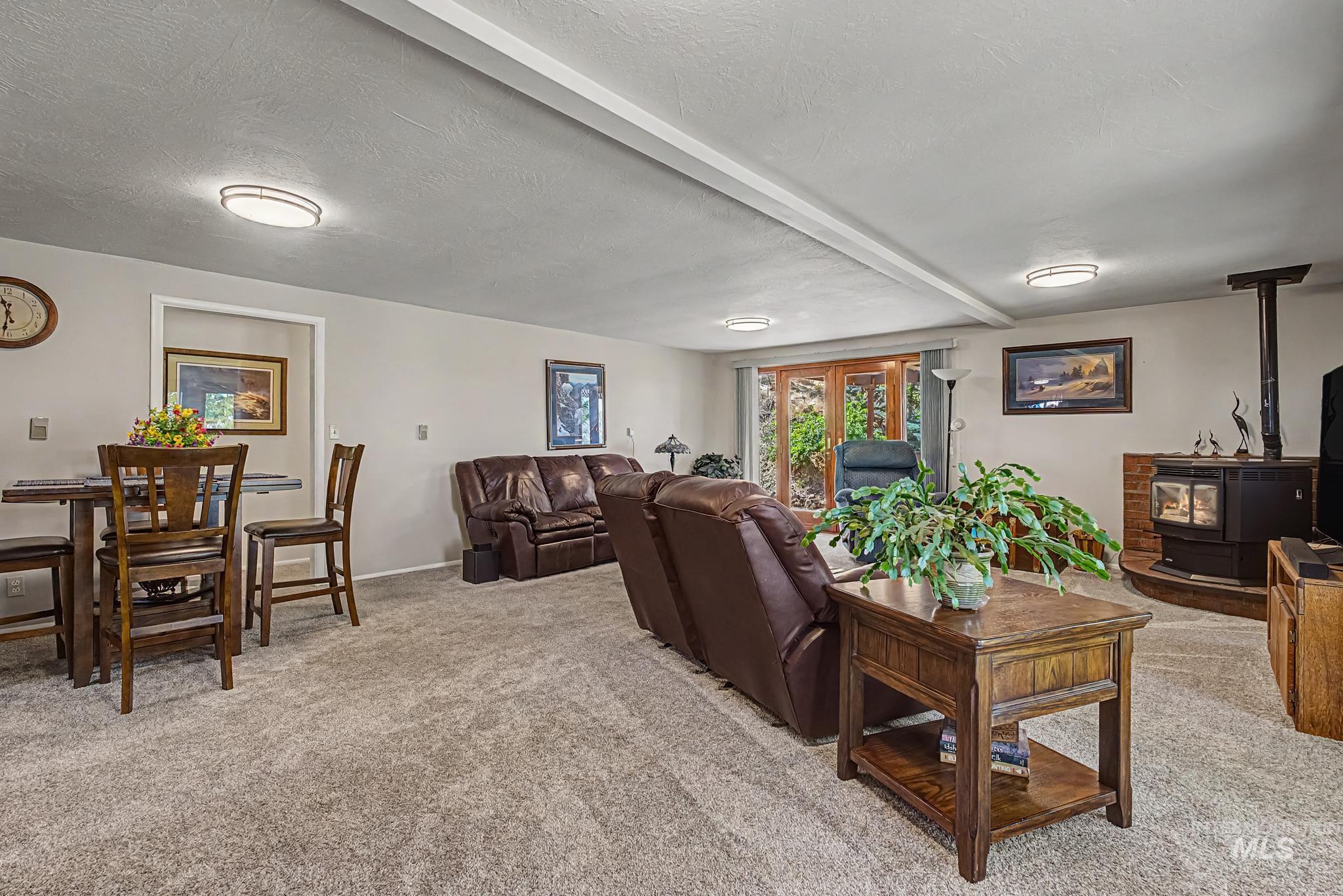 4311 Frozen Dog Road Emmett, ID 83617 - Photo 15 of 31 Spacious room featuring neutral carpet flooring, recessed lighting, and a prominent wood-burning stove with a brick-finish hearth