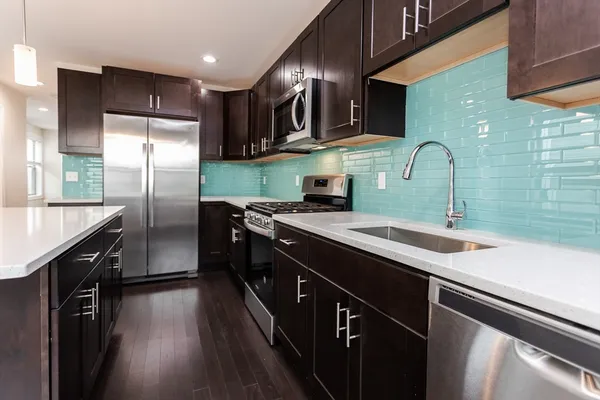 a kitchen with stainless steel appliances granite countertop a sink a stove top oven a refrigerator cabinets and wooden floor