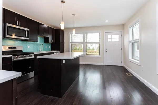 a kitchen with a sink wooden floor and black wooden cabinets