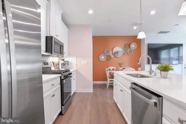 a kitchen with stainless steel appliances granite countertop a refrigerator a stove and a sink