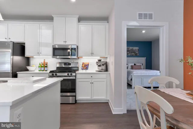 a kitchen with a sink a stove a refrigerator and white cabinets