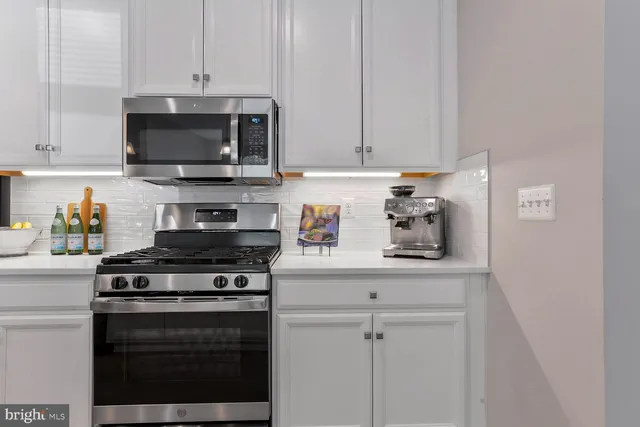 a kitchen with stainless steel appliances white cabinets and a stove top oven
