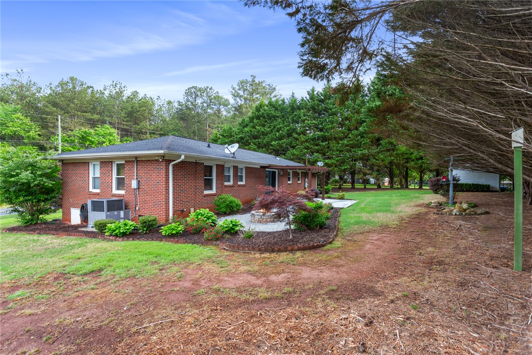 202 Keowee Trail Seneca, SC 29672 - Photo 25 of 35 This residence features a brick exterior and a well-maintained backyard with a fire pit area.