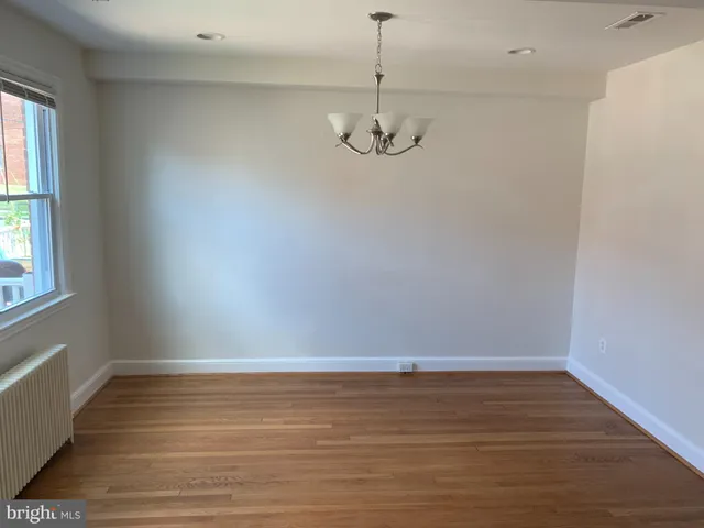 a view of empty room with wooden floor and window