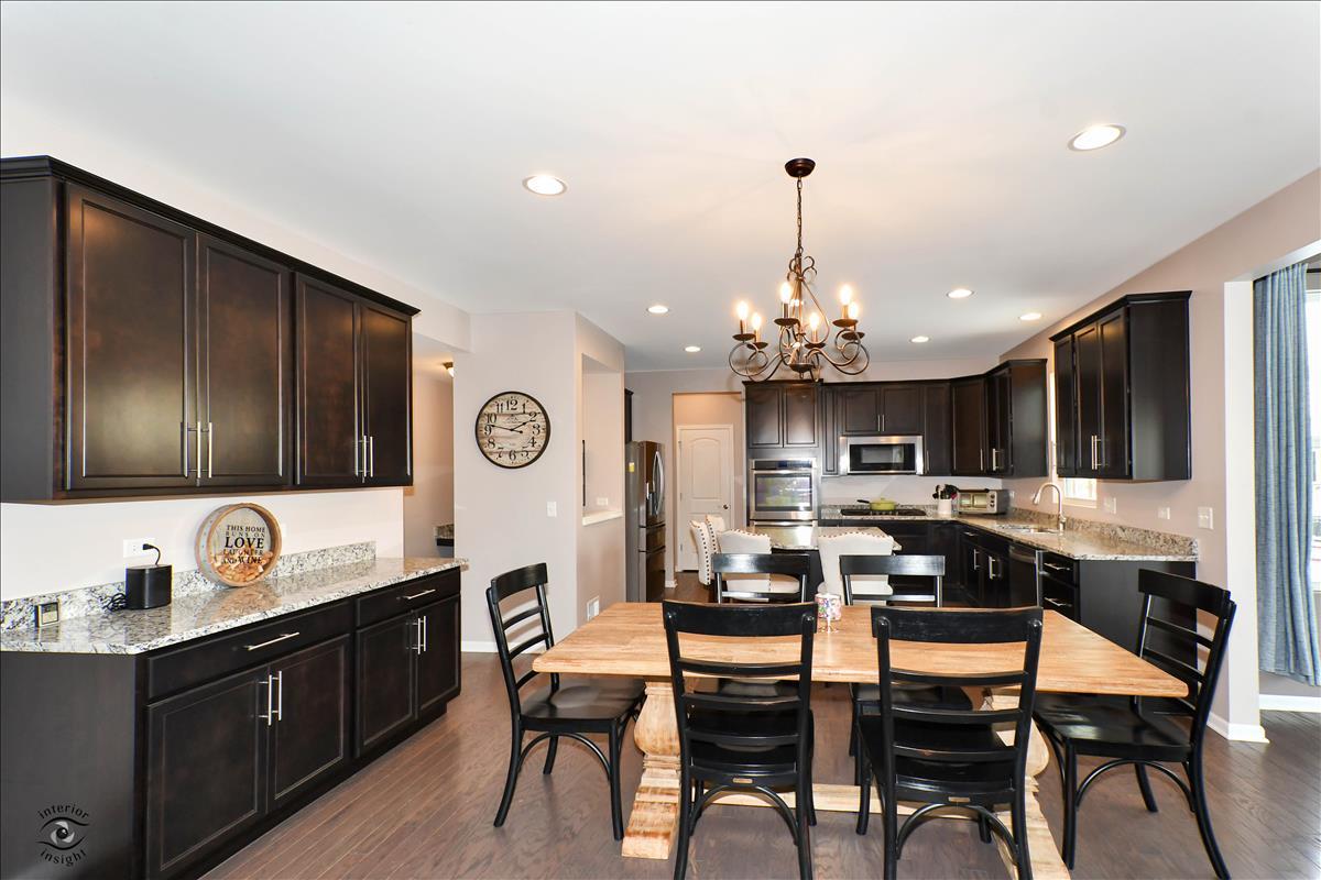 1500 Pine Drive Woodridge, IL 60517 - Photo 8 of 30 a kitchen with granite countertop lots of white cabinets a dining table and chairs