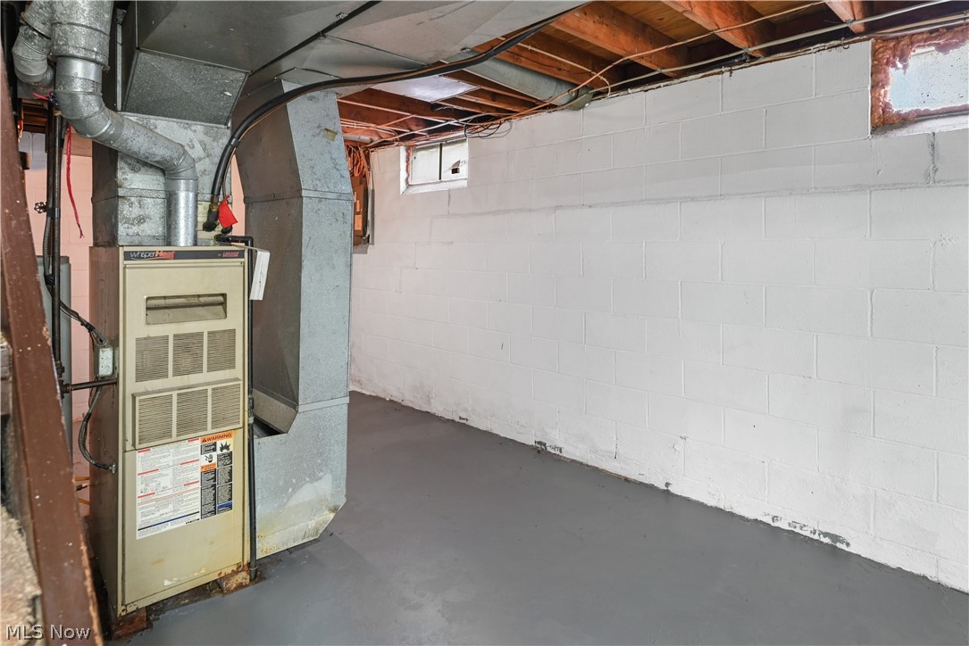 1286 Deforest Road Southeast Warren, OH 44484 - Photo 21 of 27 Utility space featuring a forced-air furnace with associated ductwork, painted concrete block walls, painted concrete flooring, an exposed ceiling with wood joists, and a small casement window