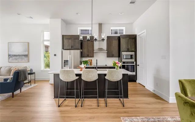 a dining room with stainless steel appliances kitchen island granite countertop a table chairs and a refrigerator