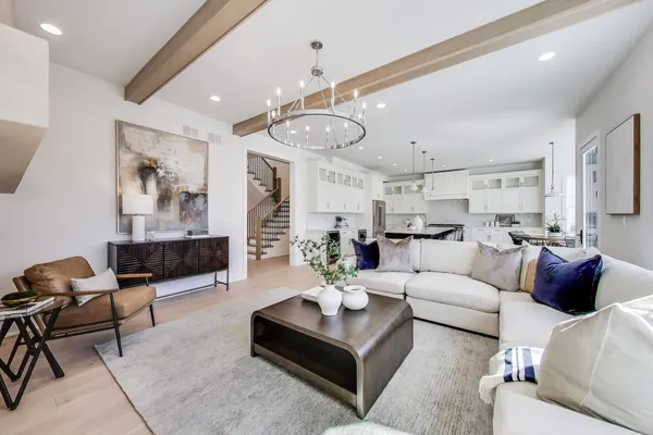 a living room with furniture kitchen view and a chandelier