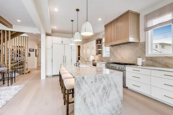 a large kitchen with granite countertop a stove a sink a dining table and chairs with wooden floor