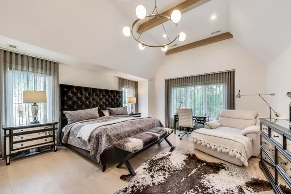 a bedroom with a bed a chandelier and dresser