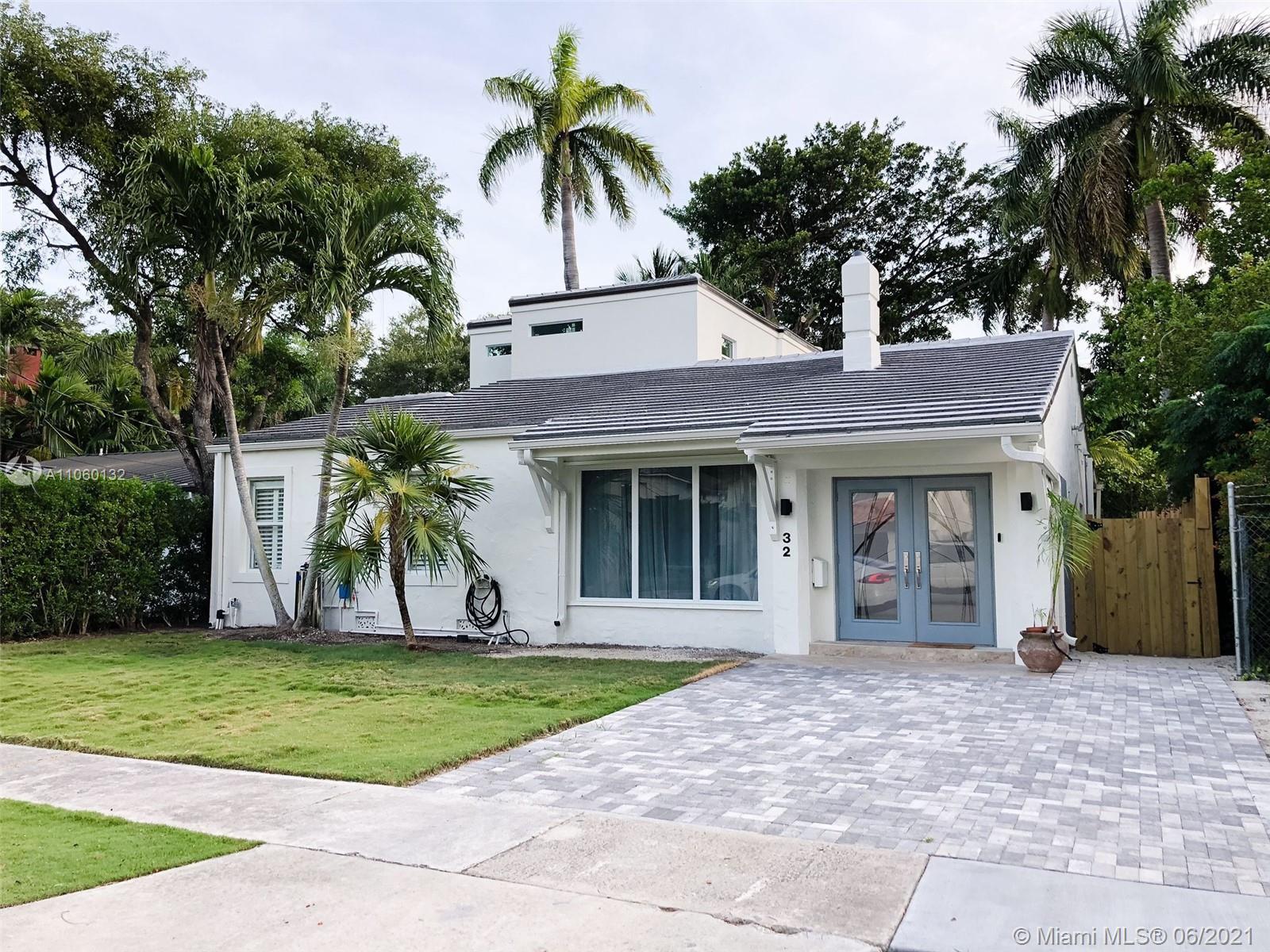 a front view of a house with a yard and palm trees